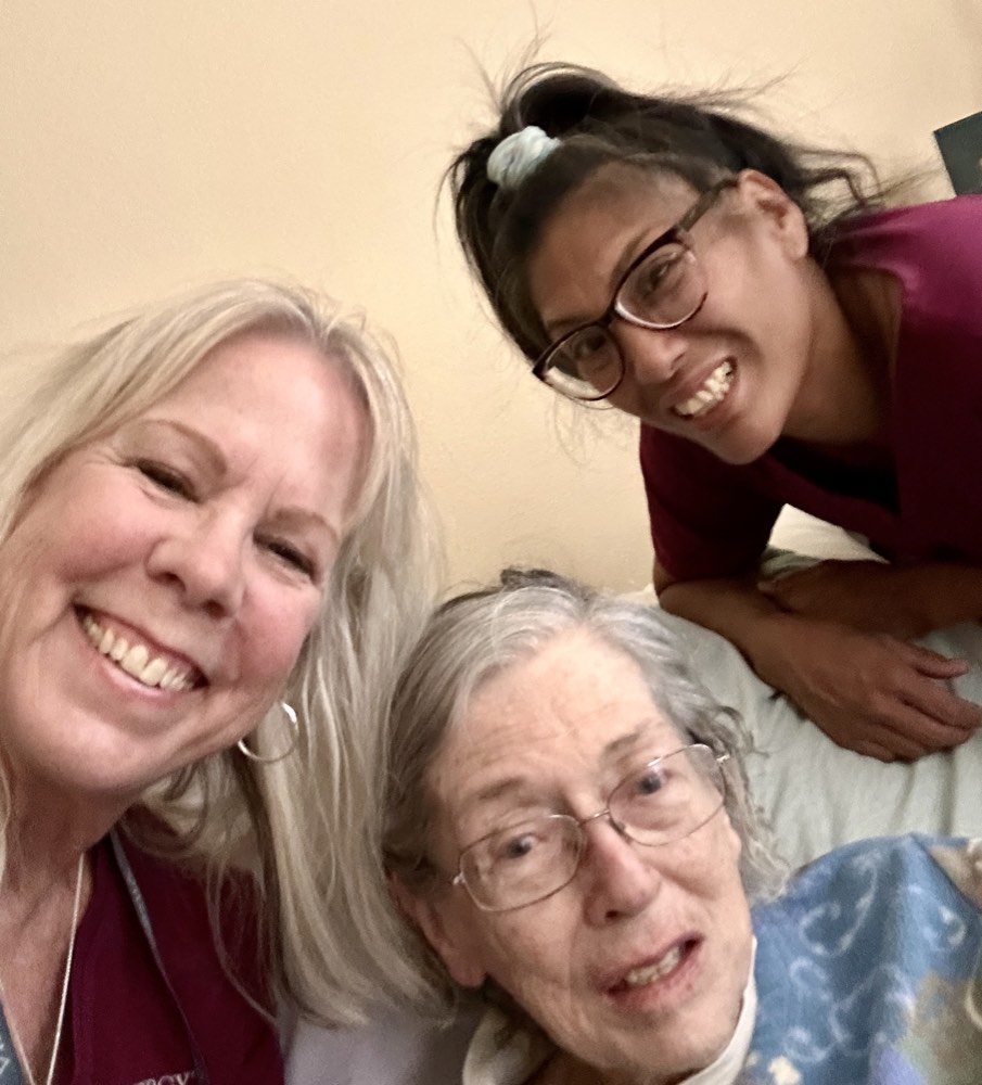Two caregivers and their client laughing together for a selfie