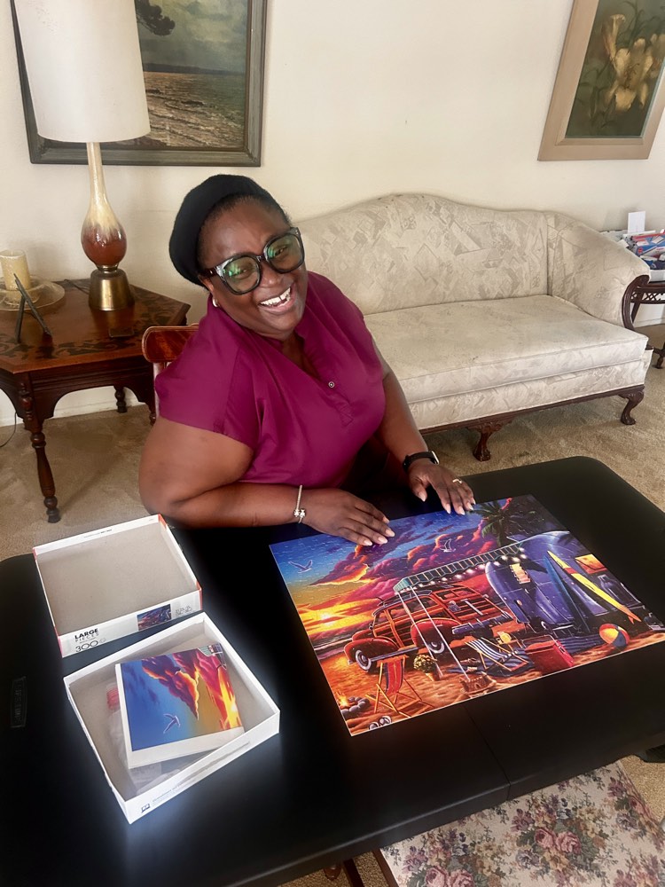 A caregiver smiling while working on a jigsaw puzzle with a client
