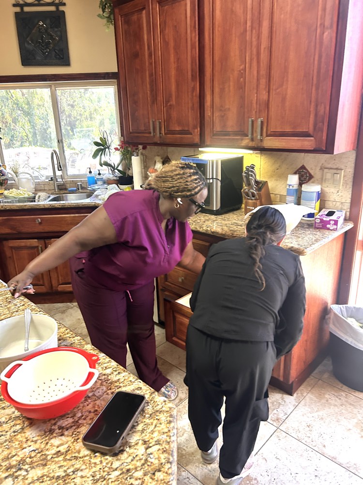 Two caregivers preparing a meal together in a client’s kitchen